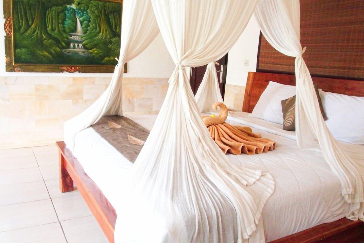 A bed with a canopy, a painting on the wall, and a wooden bench.