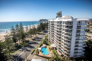 A high-rise hotel with a pool, beachfront view, and multiple balconies.