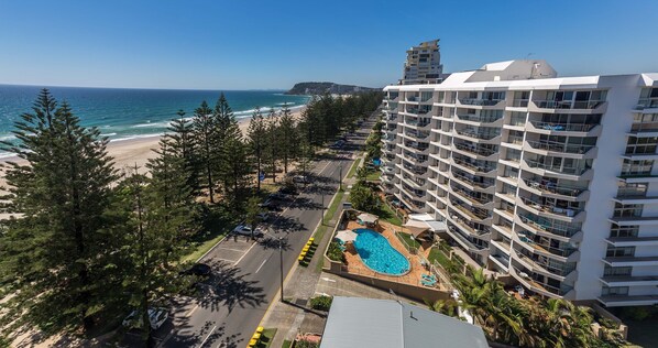 A high-rise hotel with a pool and beach view.