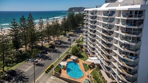 A high-rise hotel with a swimming pool, beach view, and multiple balconies. - Solnamara Beachfront Apartments (Burleigh Heads)