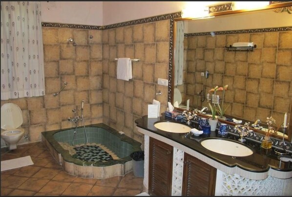 Un baño con bañera, dos lavamanos, un inodoro y un espejo grande.