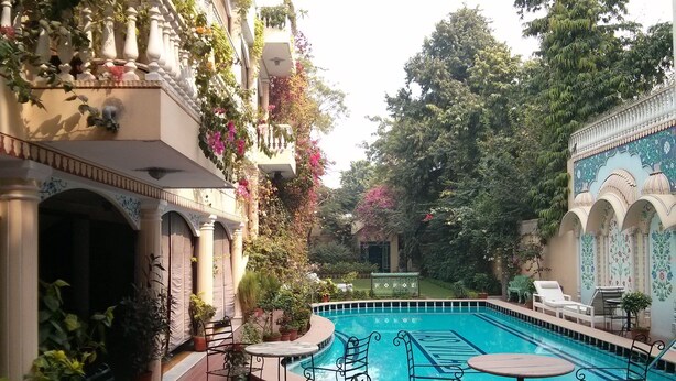 Un área de piscina con suelo de baldosas, sillas y mesas de metal.