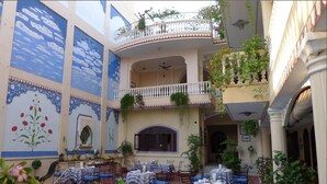 Un patio de varios niveles con mobiliario exterior, piscina y murales decorativos.