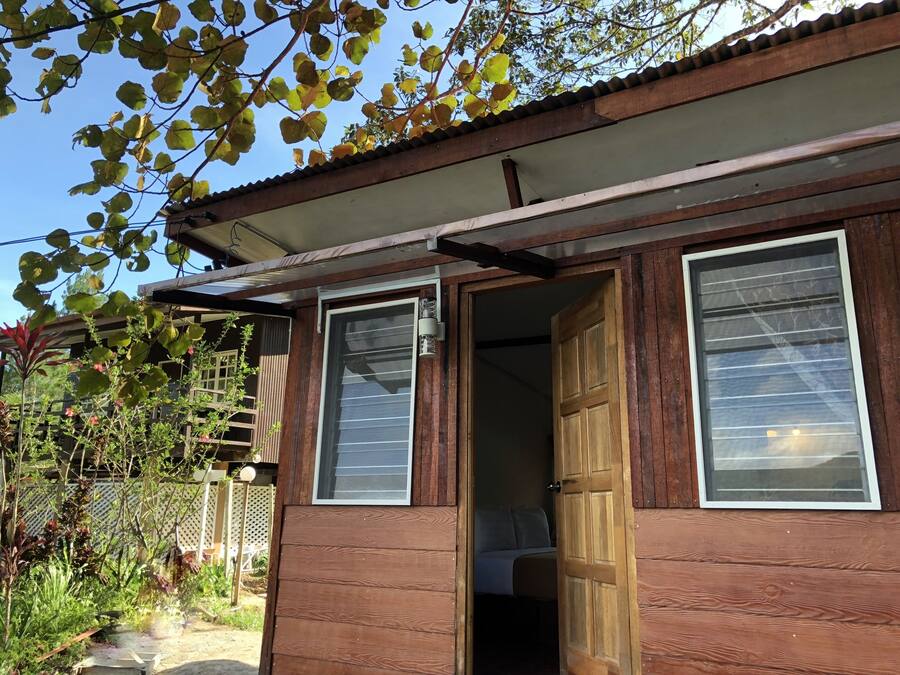 A wooden building with a covered porch, a door leading inside, and a view of the outdoors.
