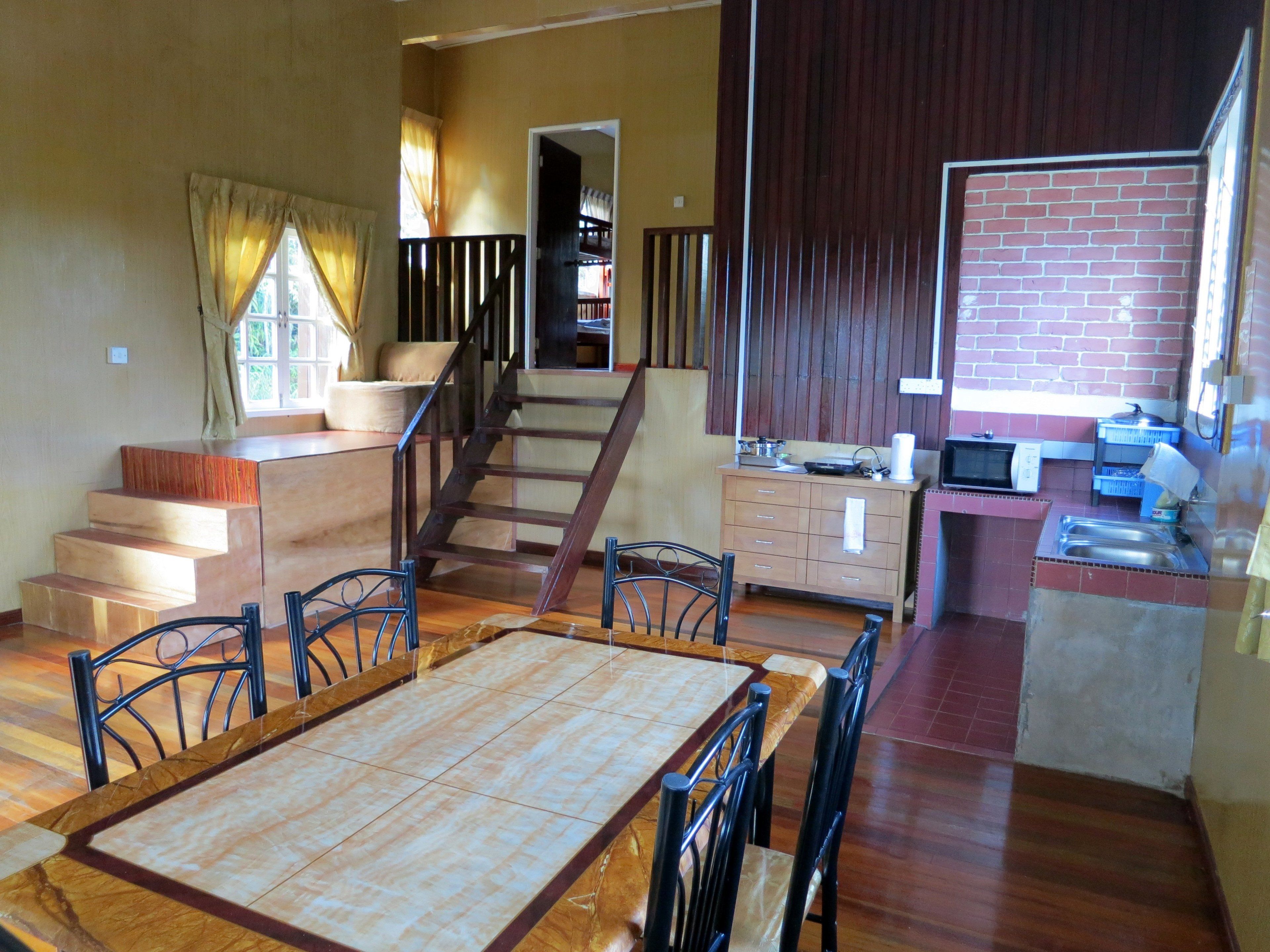 A spacious living area with a dining table, chairs, a staircase, and a kitchen area.
