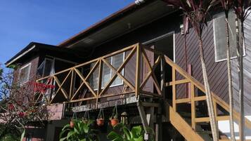 A two-story house with a wooden deck and a staircase leading to the second floor.