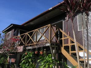 A two-story house with a wooden deck and a staircase leading to the second floor. - Mile 36 Lodge (Ranau)
