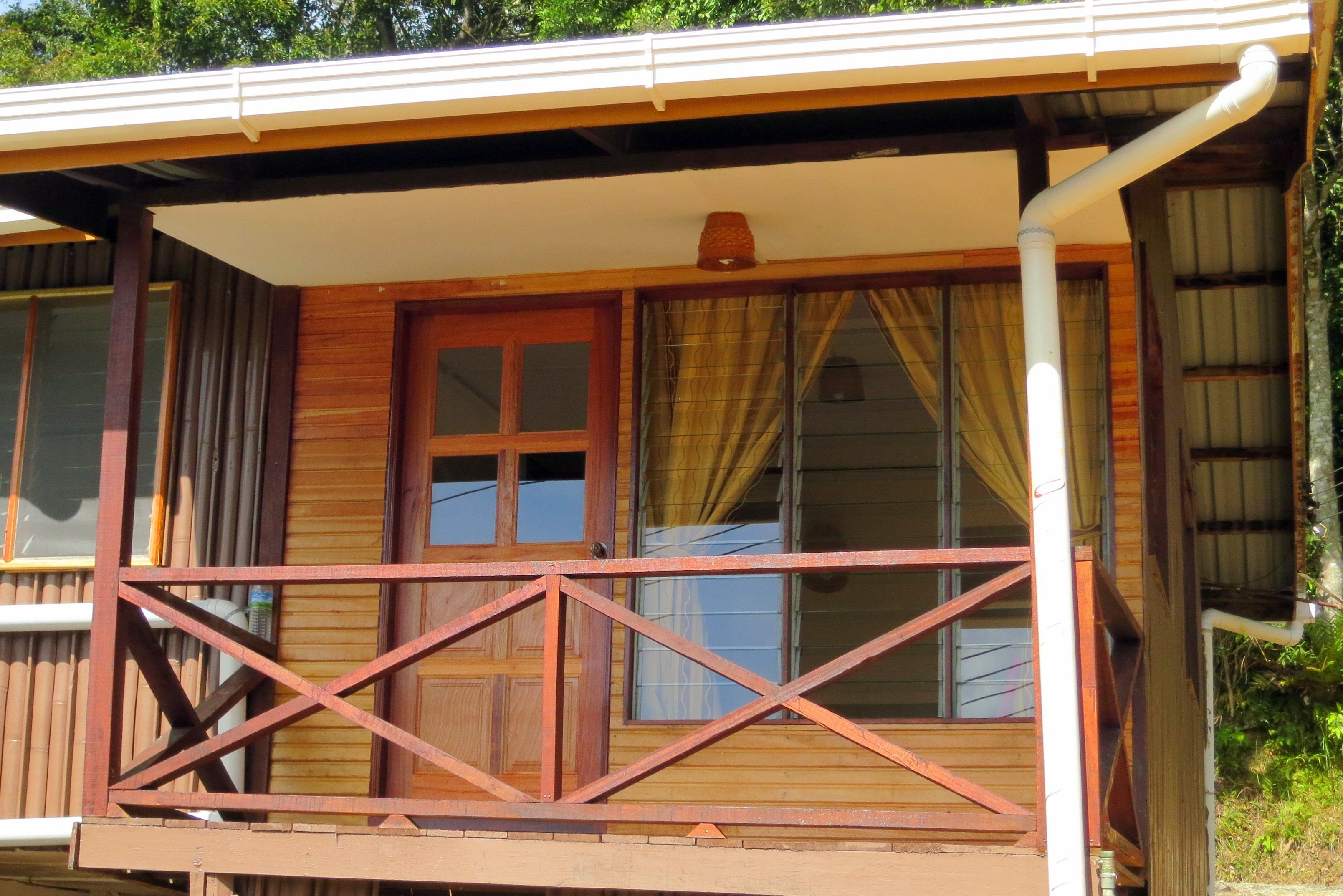 Une cabane en bois dotée d’un balcon, de grandes fenêtres et d’une porte.
