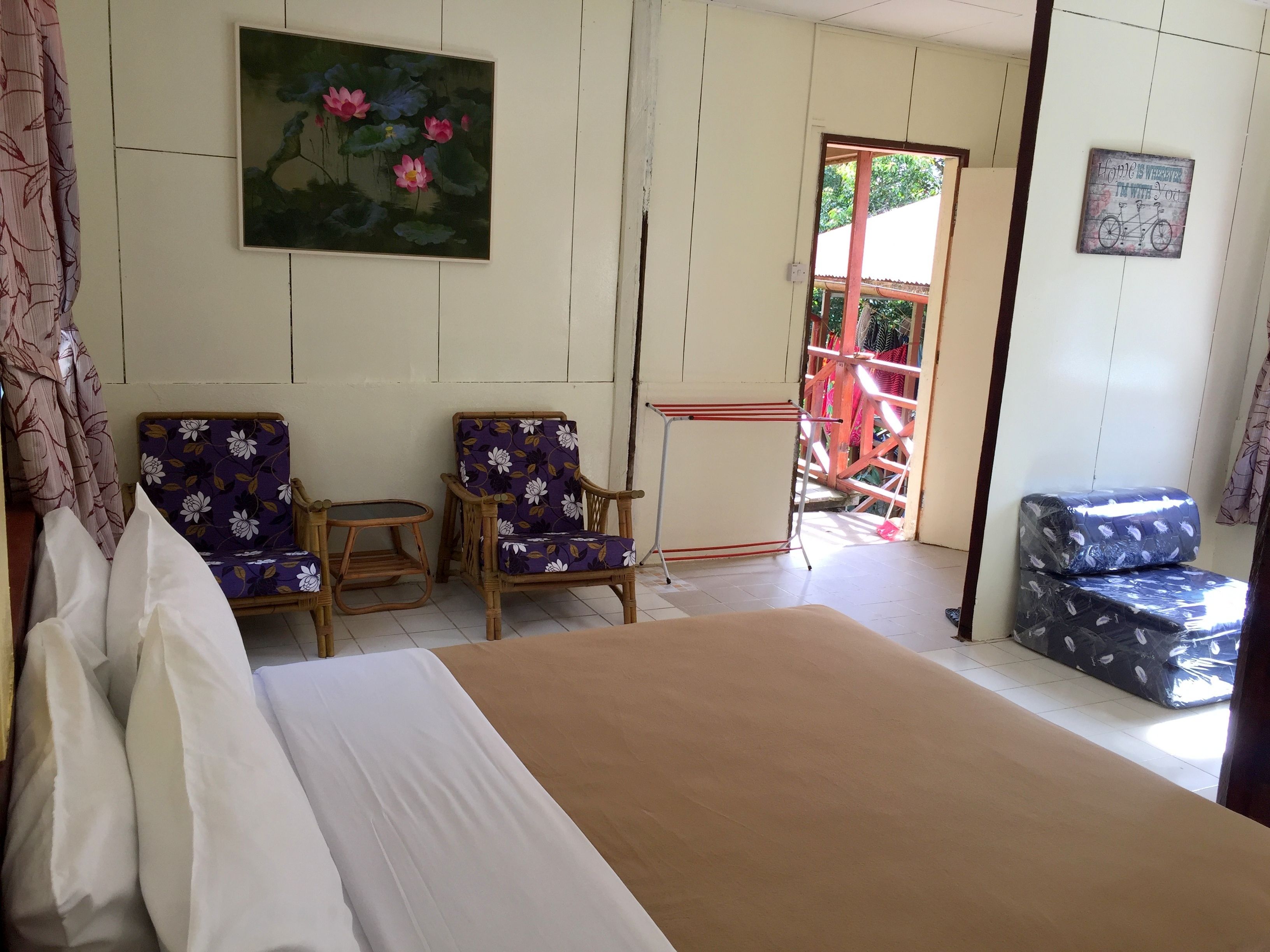 Una habitación con una cama, dos sillas, una mesita, un cuadro y vistas al exterior.