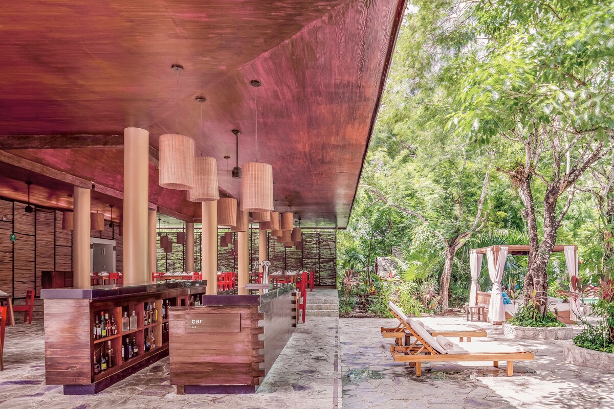 A bar area with wooden shelves, red chairs, and a canopy overhead. - The Explorean Cozumel - All Inclusive (Cozumel)