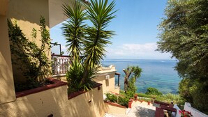 A coastal staircase with a view of the sea, surrounded by greenery and a building with a red roof. - Batelo Boutique Hotel - Adults Only (Corfu)