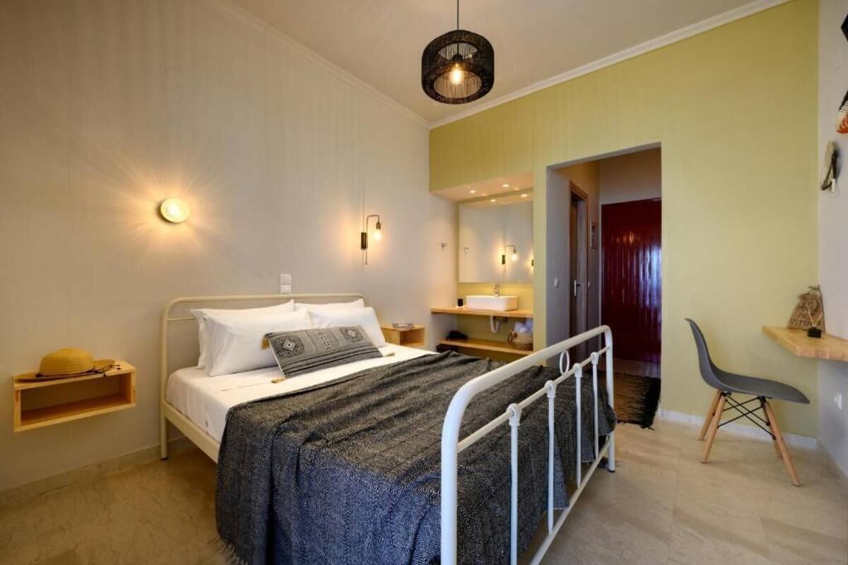 Un dormitorio con cama, mesita de noche, lámpara y una silla.