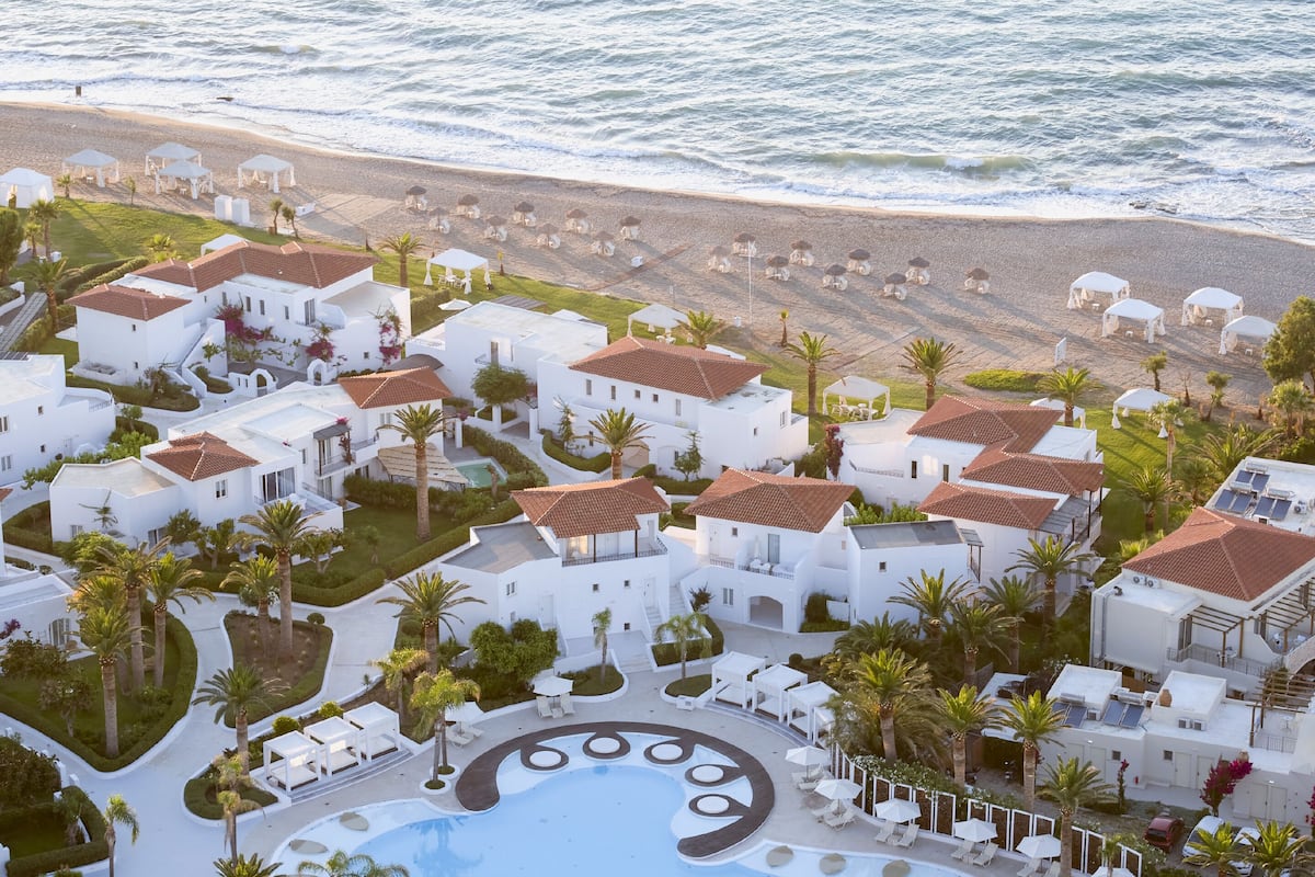 Un complejo turístico con edificios blancos, piscina y playa.