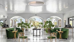 A spacious lobby with green sofas, gold chairs, and a central table.
