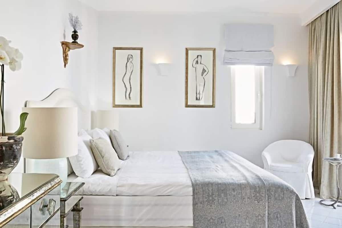 Un dormitorio con cama, una silla, una lámpara y decoración en la pared.