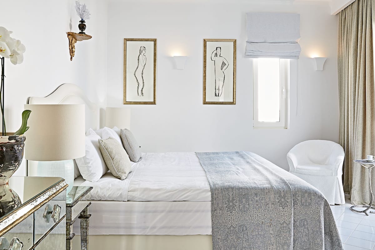 Un dormitorio moderno con una cama grande, una mesita de noche, una silla y obras de arte en las paredes.