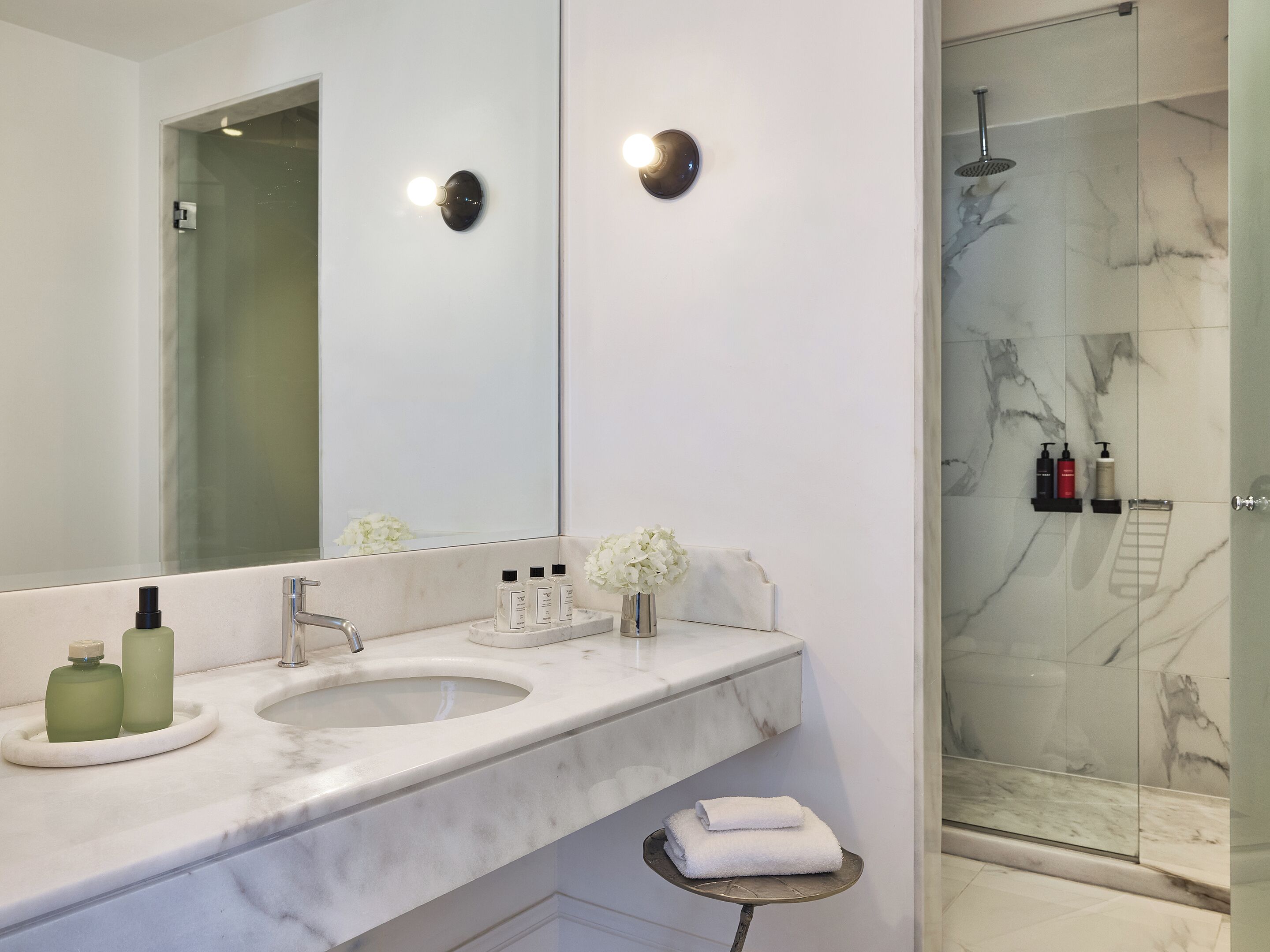 A modern bathroom with two sinks, a large mirror, and a glass-enclosed shower.