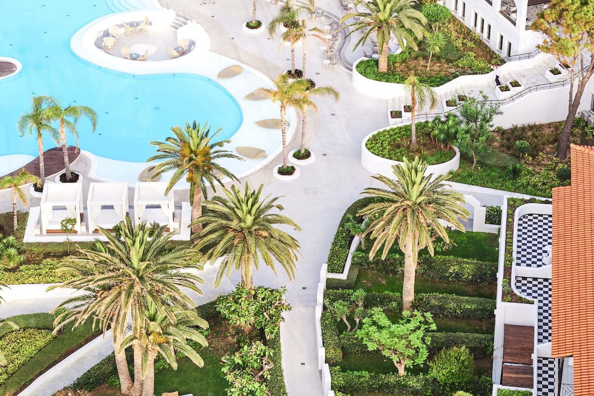Un resort con piscina central, palmeras y zonas de estar al aire libre.