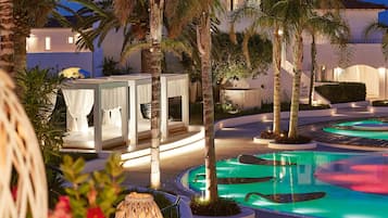 Una piscina al aire libre, sombrillas, sillones reclinables de piscina