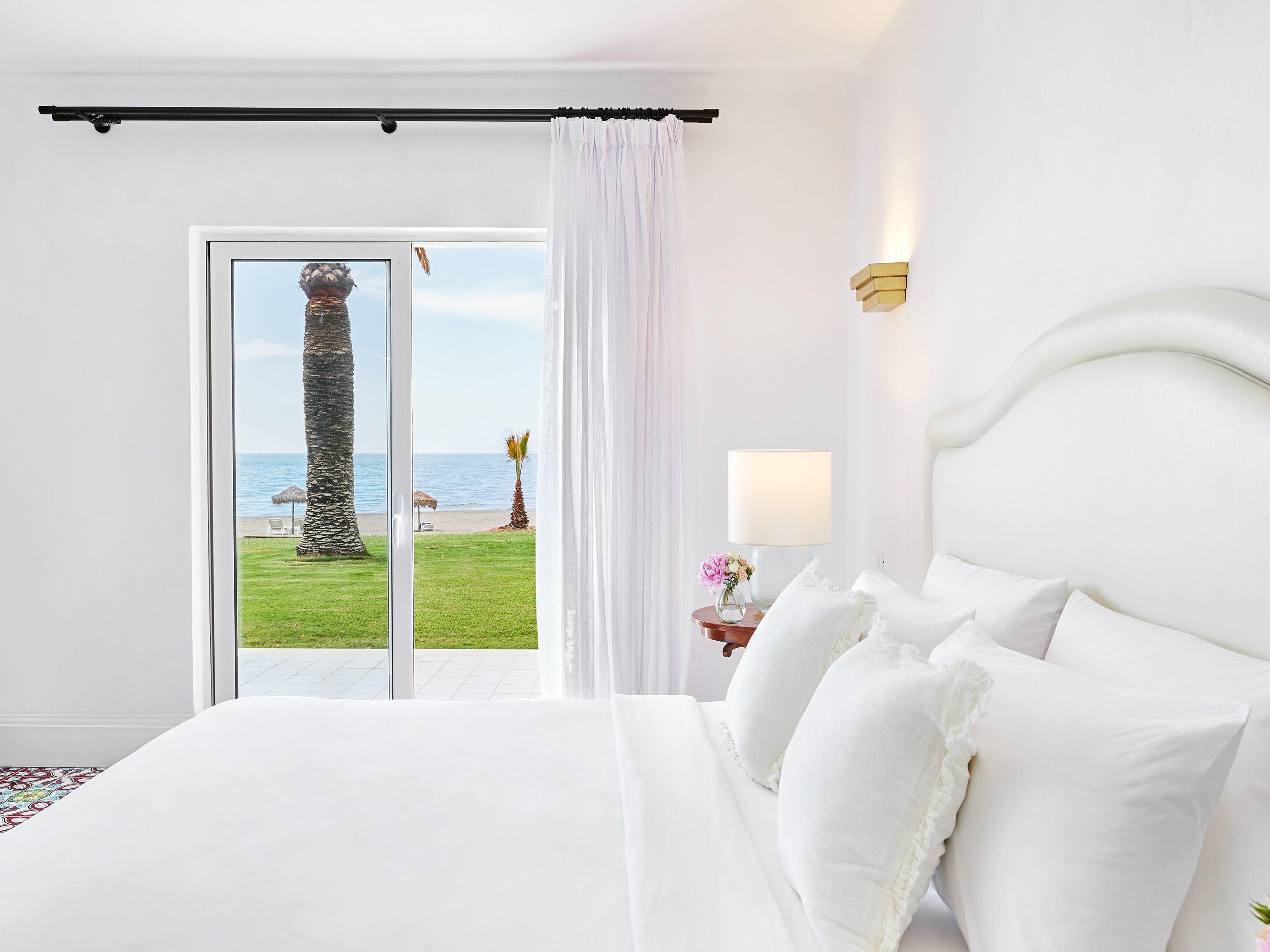 Une chambre d’hôtel avec un grand lit, une vue sur la plage et une porte-fenêtre coulissante.