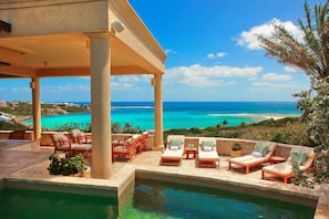 Ein Poolbereich mit Liegestühlen und Blick aufs Meer.