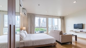 Een hotelkamer met een groot bed, een bank, een televisie en een raam met uitzicht over de stad.