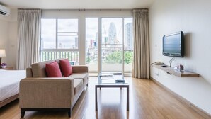 Een hotelkamer met een bed, een bank en een aan de muur bevestigde televisie.