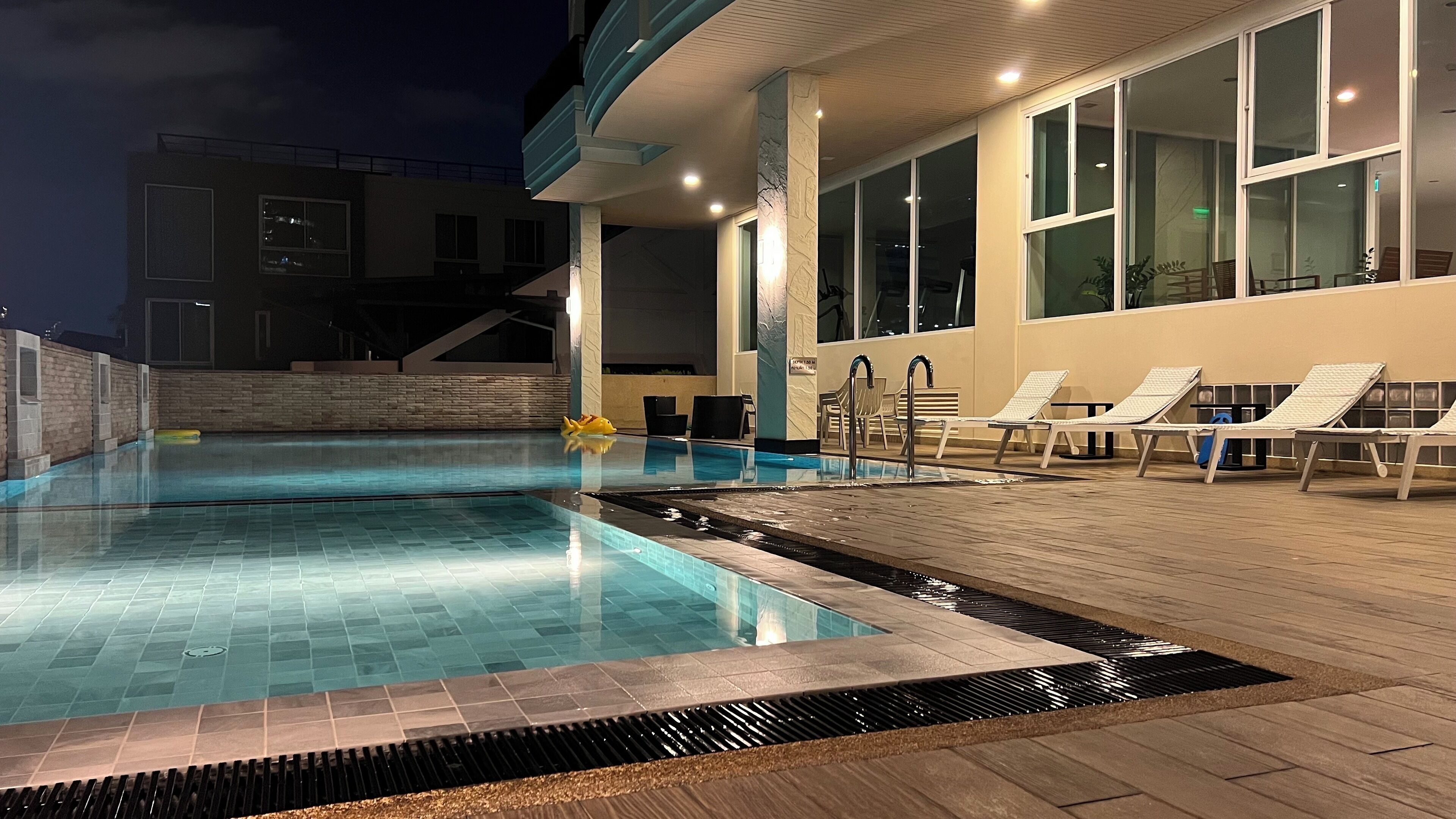 Piscina com espreguiçadeiras e deck de madeira.