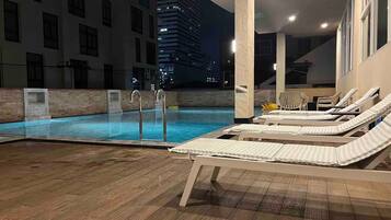 Una piscina al aire libre, sillones reclinables de piscina