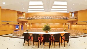 Una amplia sala de conferencias con techo alto, múltiples zonas de estar y una mesa central con sillas.