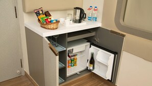 A compact kitchenette with a refrigerator, a coffee maker, and a small countertop with snacks and drinks.