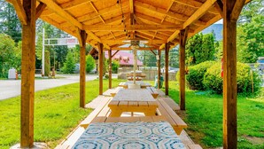 A wooden pavilion with picnic tables and a patterned mat on the ground. - Holiday Motel & RV Resort (Hope)