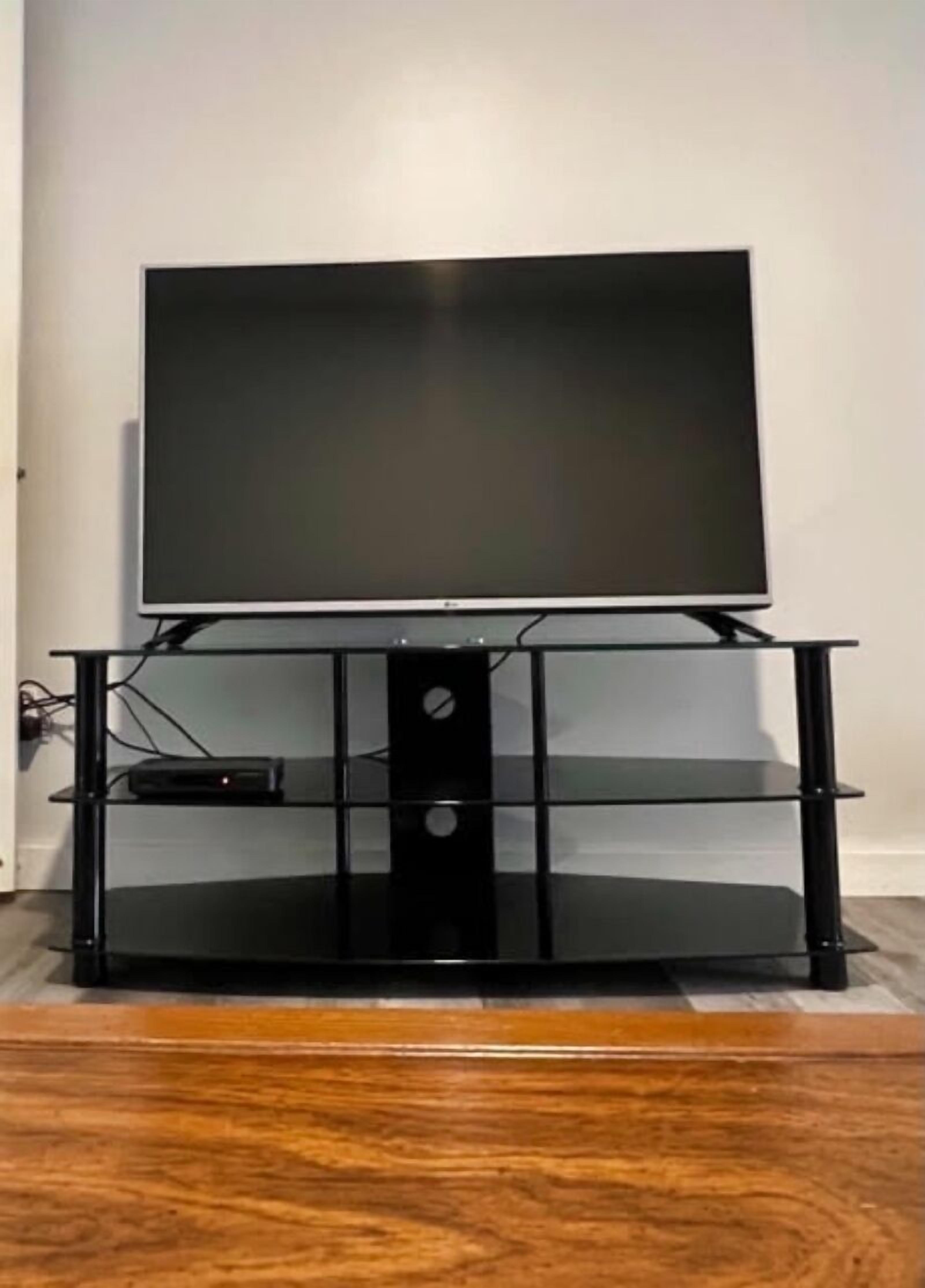 A black entertainment center with a flat-screen TV and a media player on the lower shelf.