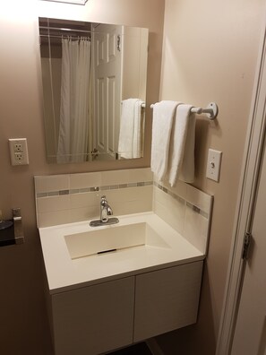 A bathroom with a white sink, a mirror, a towel rack, and a shower curtain.