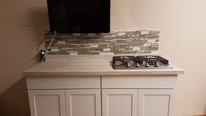 A kitchen with a tiled backsplash, a gas stove, and a flat-screen TV mounted above the counter. - Holiday Motel & RV Resort (Hope)