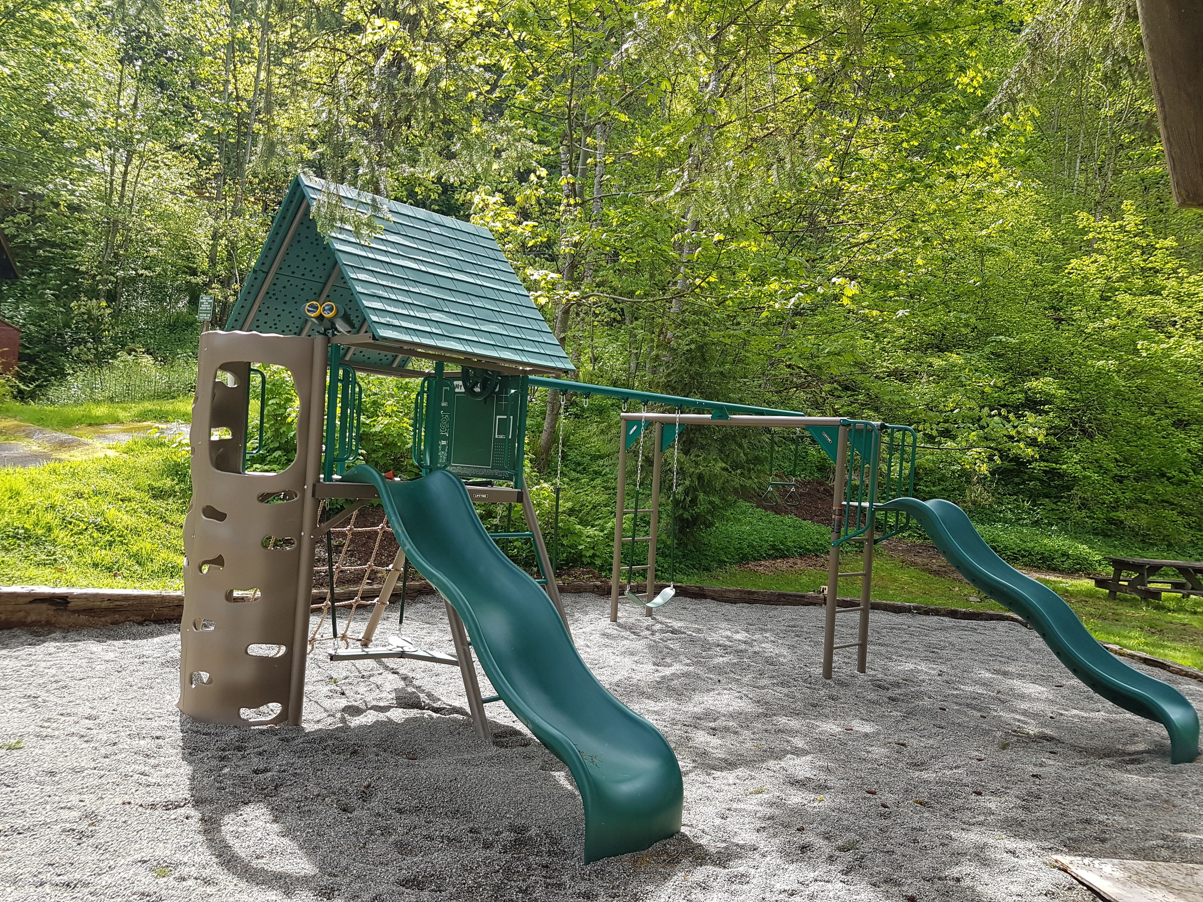 A playground with two slides, a climbing structure, and a picnic table.
