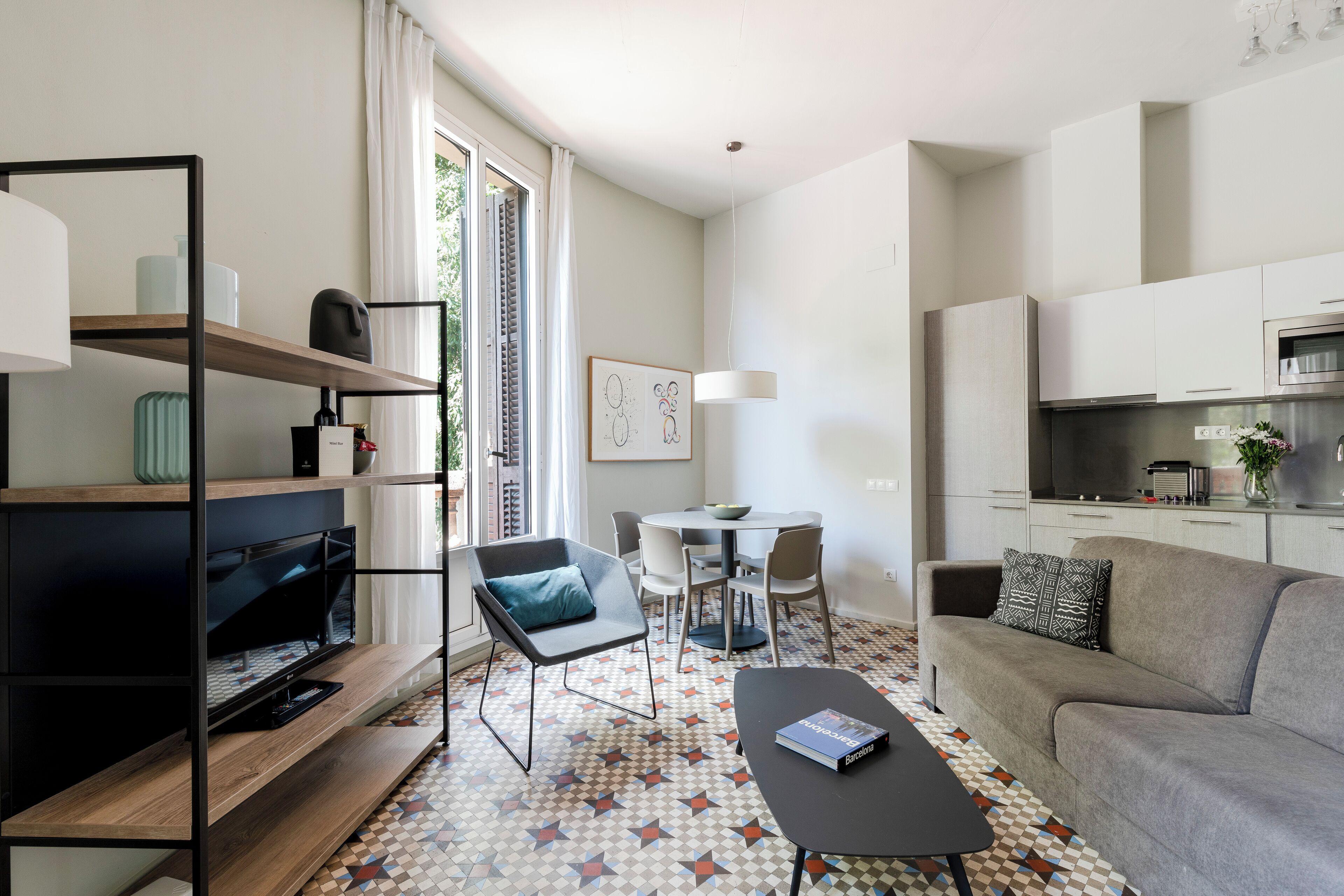 Un salon moderne comprenant un téléviseur, un canapé, une table basse et un coin repas avec des chaises et une table.
