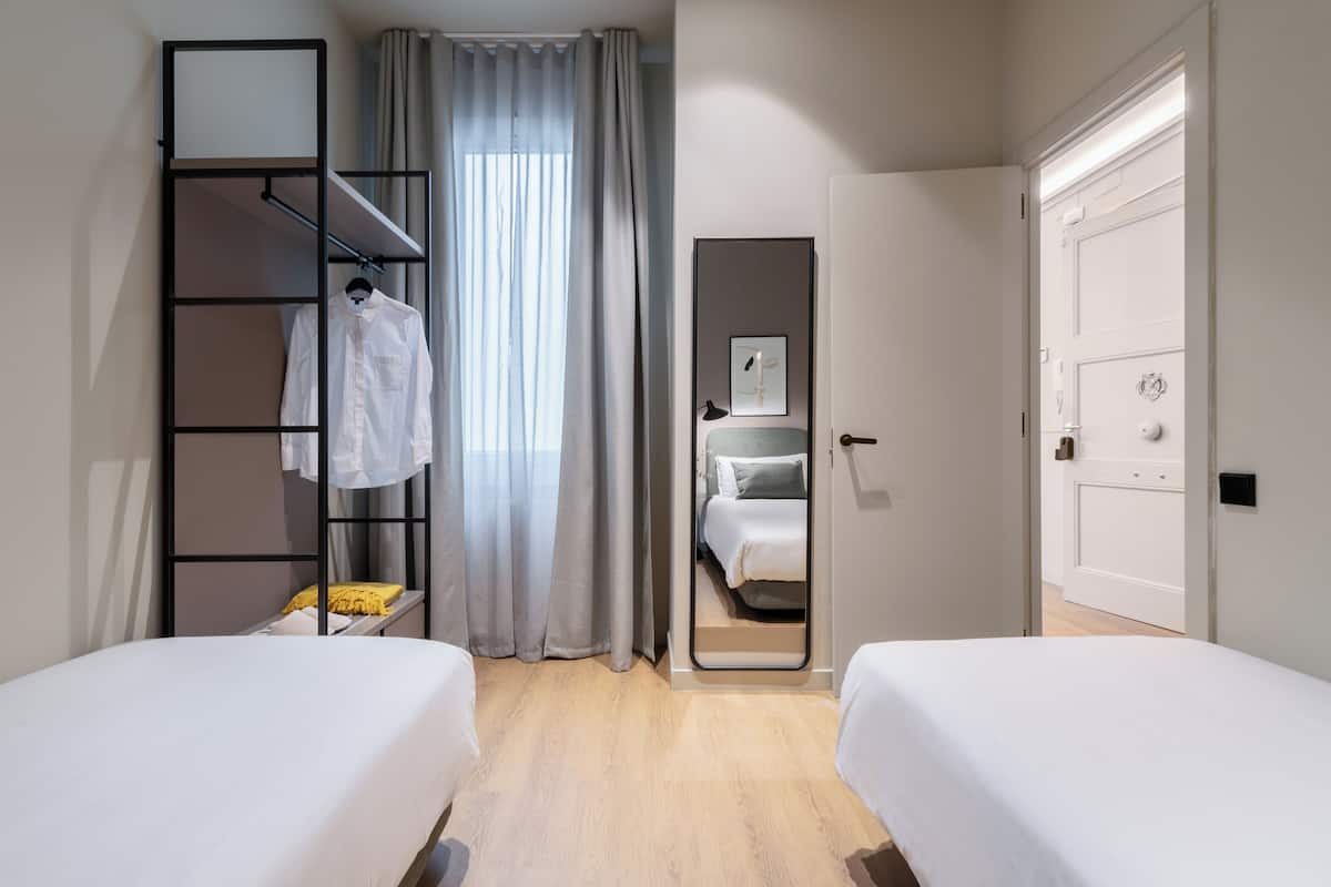 Una habitación de hotel con dos camas, un armario, un espejo y una puerta.