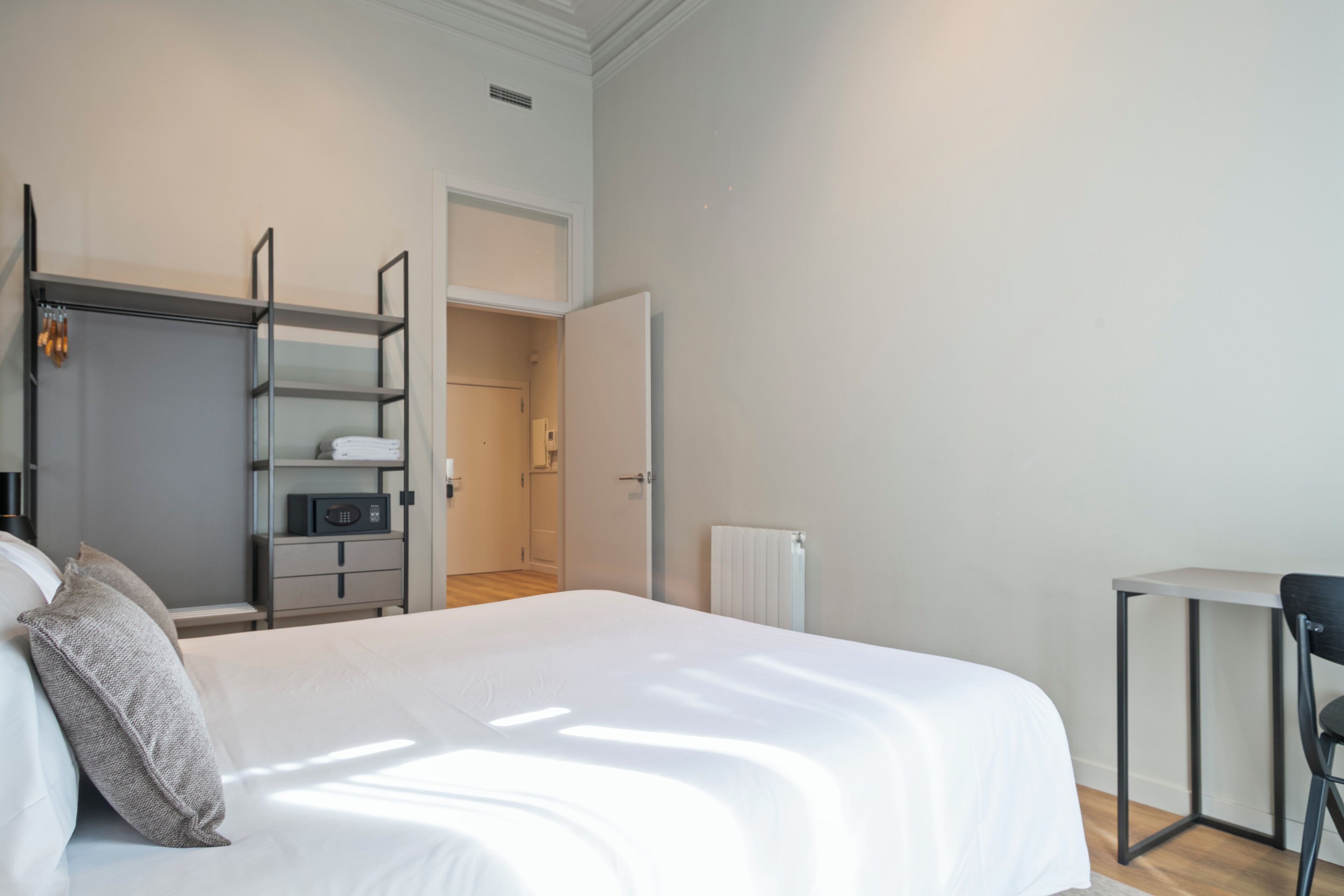 A bedroom with a bed, a wardrobe, a desk, and a radiator.