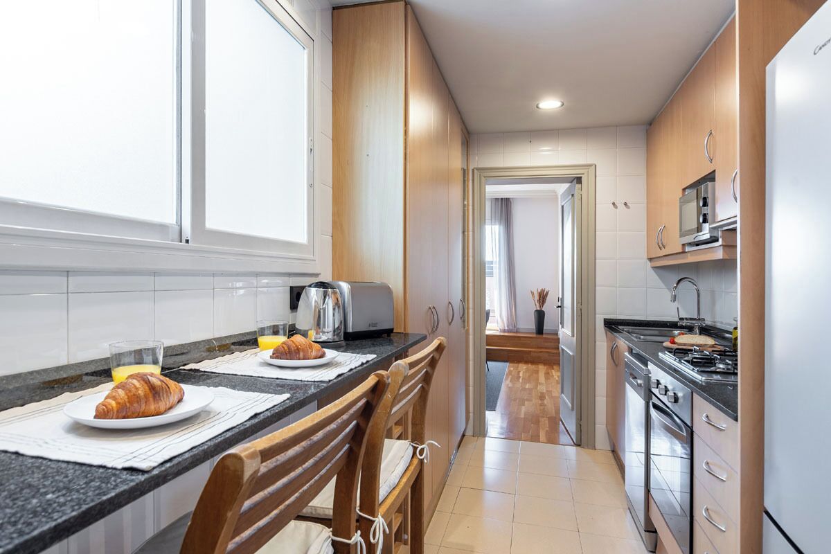 A modern kitchen with wooden cabinets, a black countertop, and stainless steel appliances.