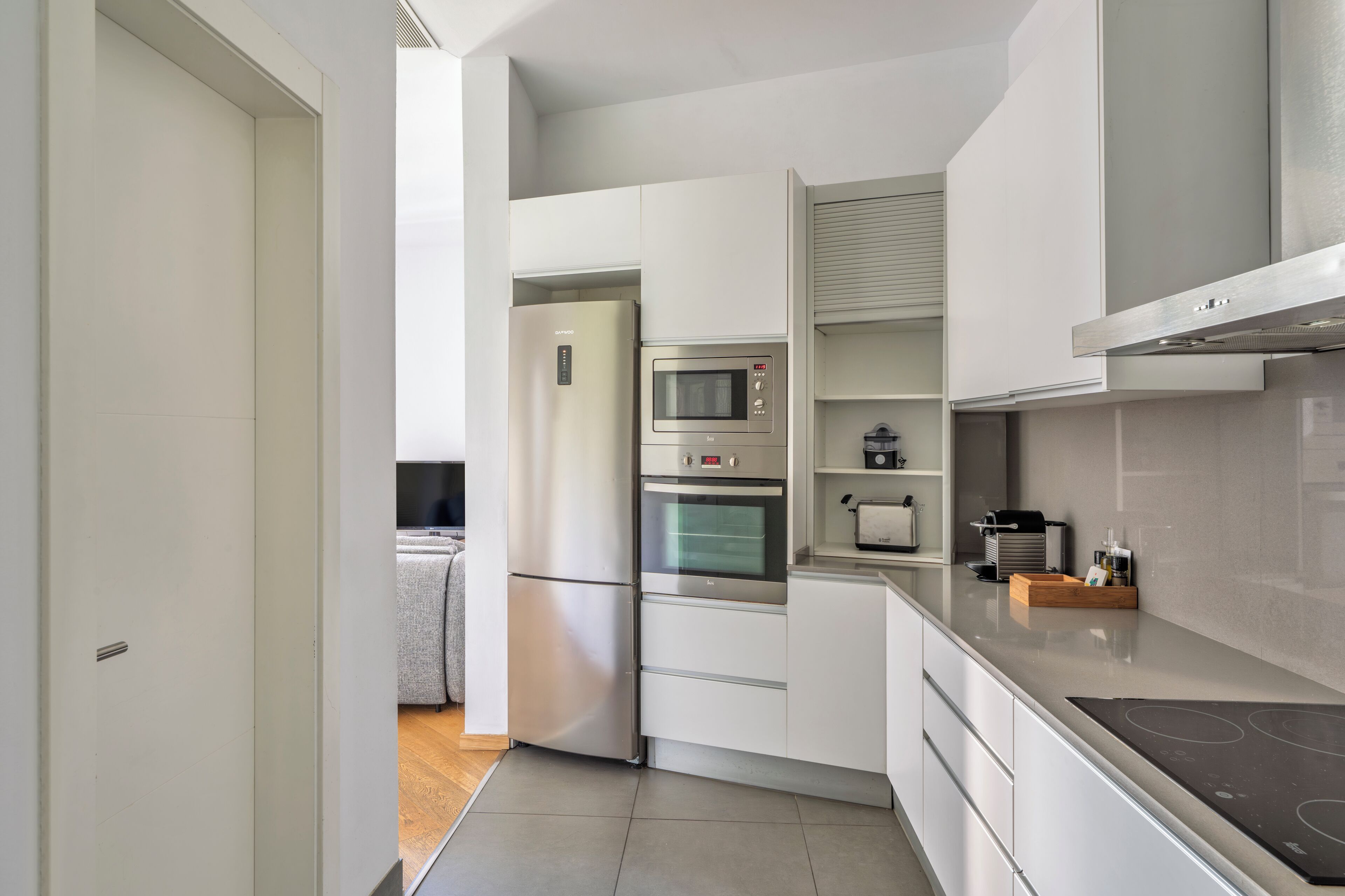 A modern kitchen with white cabinetry, a built-in oven, a microwave, and a stovetop.