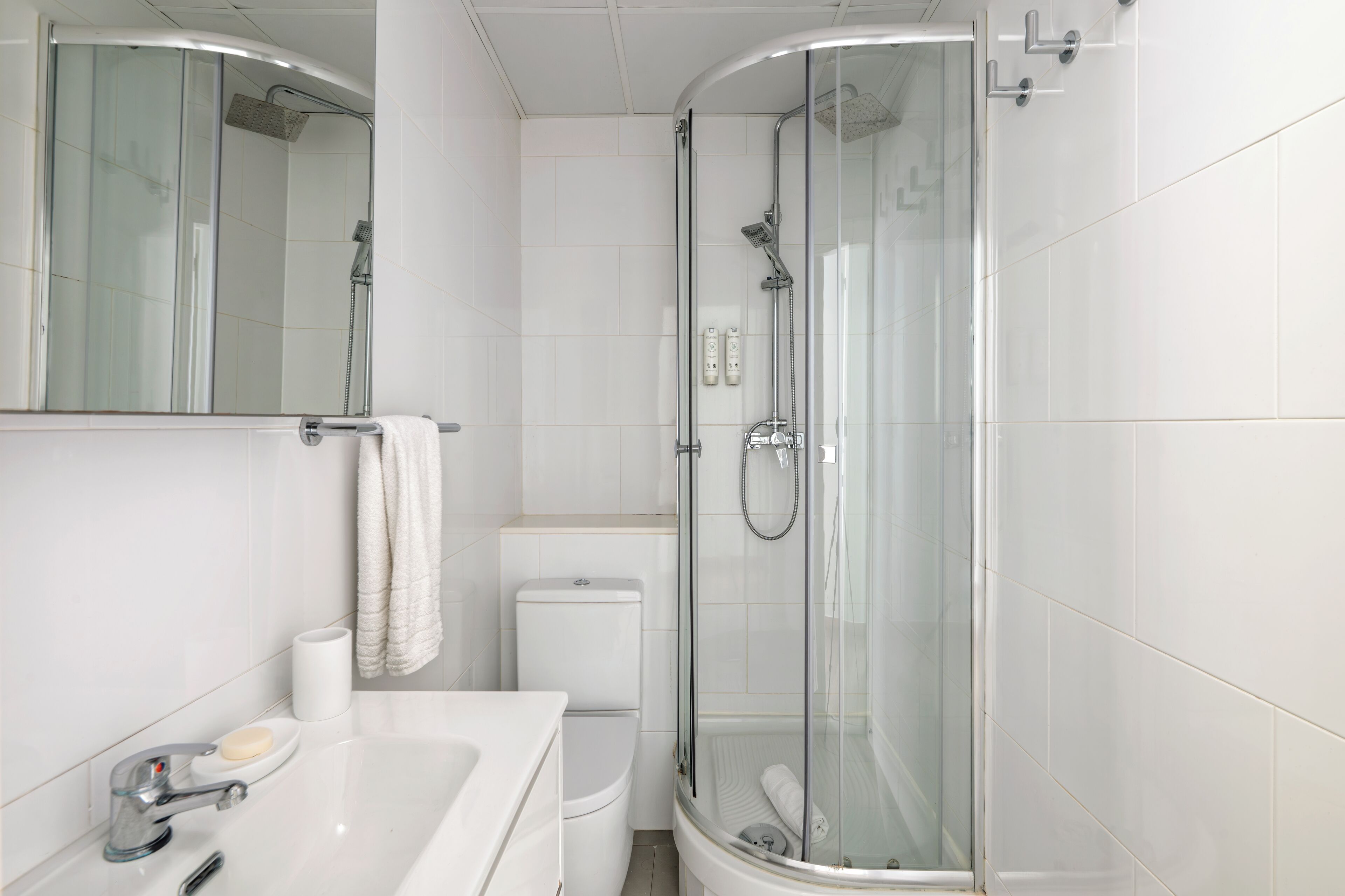 Un baño moderno con ducha envuelta en vidrio, inodoro y lavabo con espejo.