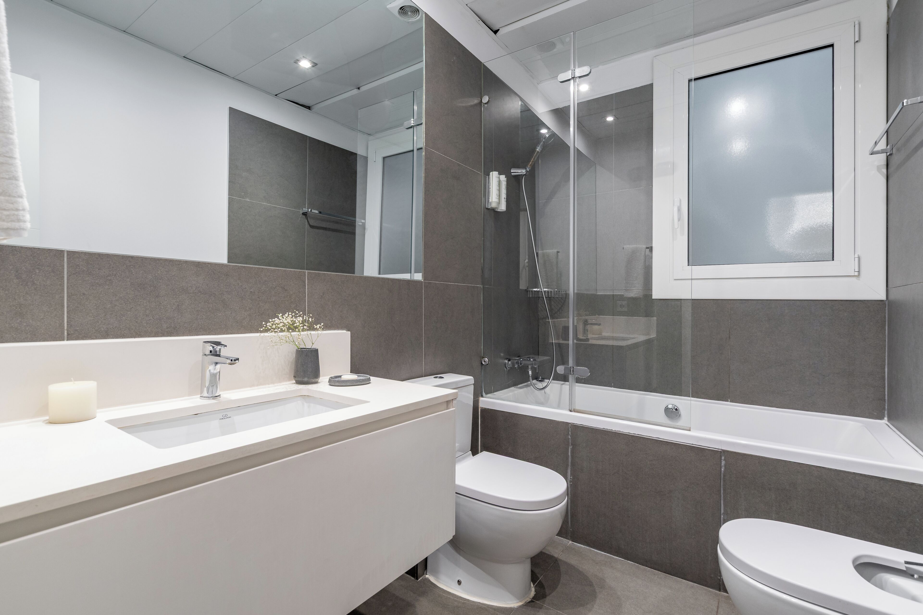 A modern bathroom with a white sink, toilet, and bathtub.