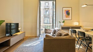 A modern living room with a sofa, TV, and dining area. - Aspasios Rambla Catalunya Suites  (Barcelona)