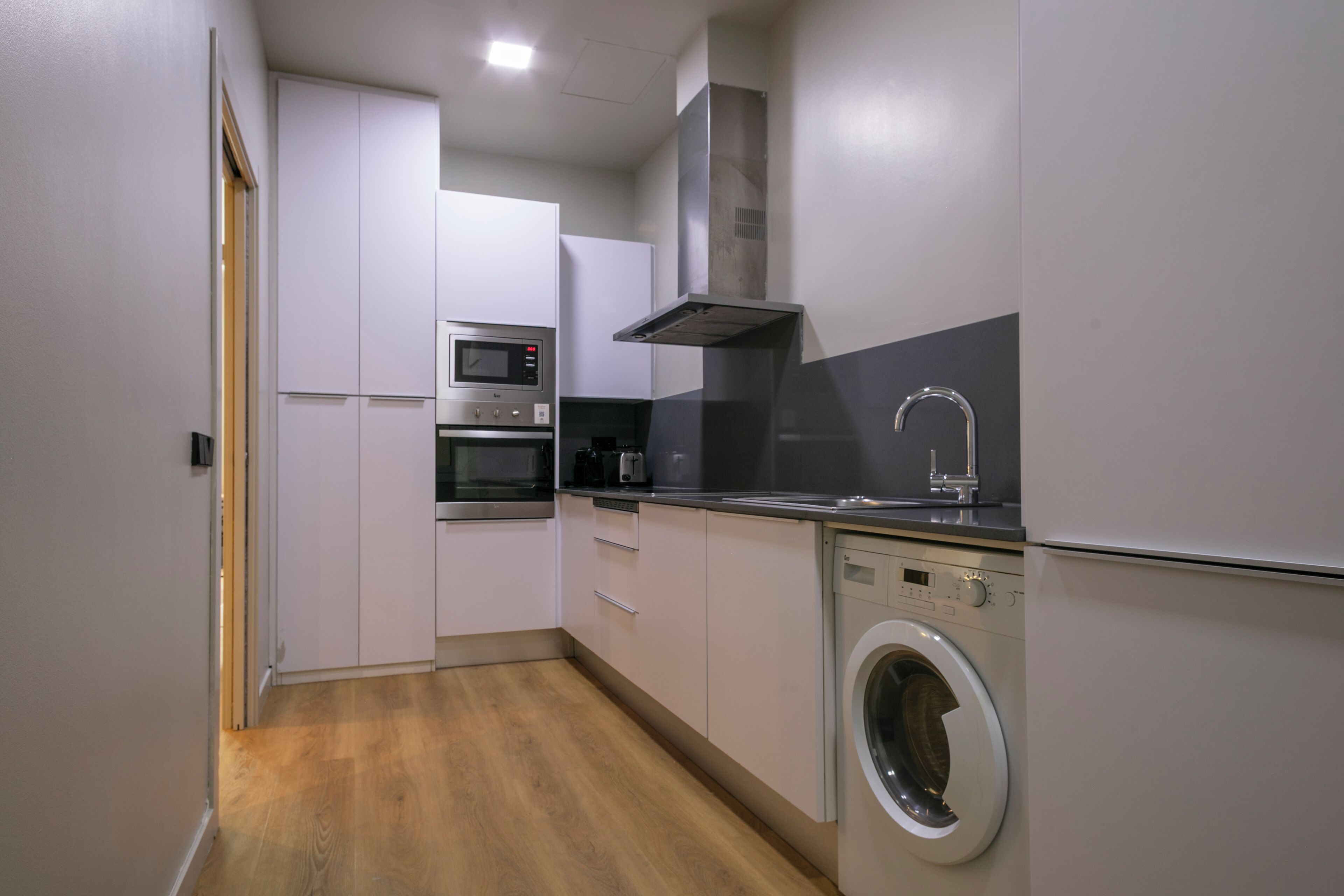 A compact kitchen with a microwave, oven, and washing machine.