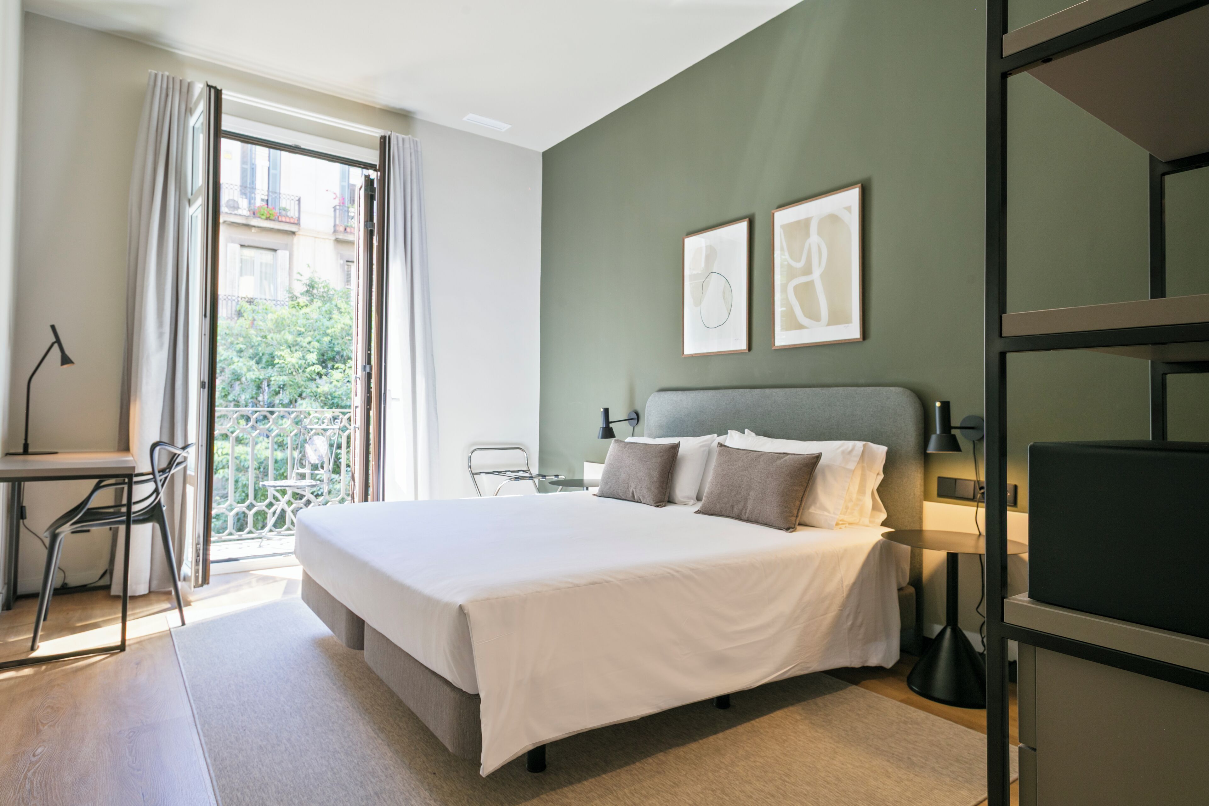 Une chambre d’hôtel avec un lit, un bureau, une chaise et un balcon offrant une vue.