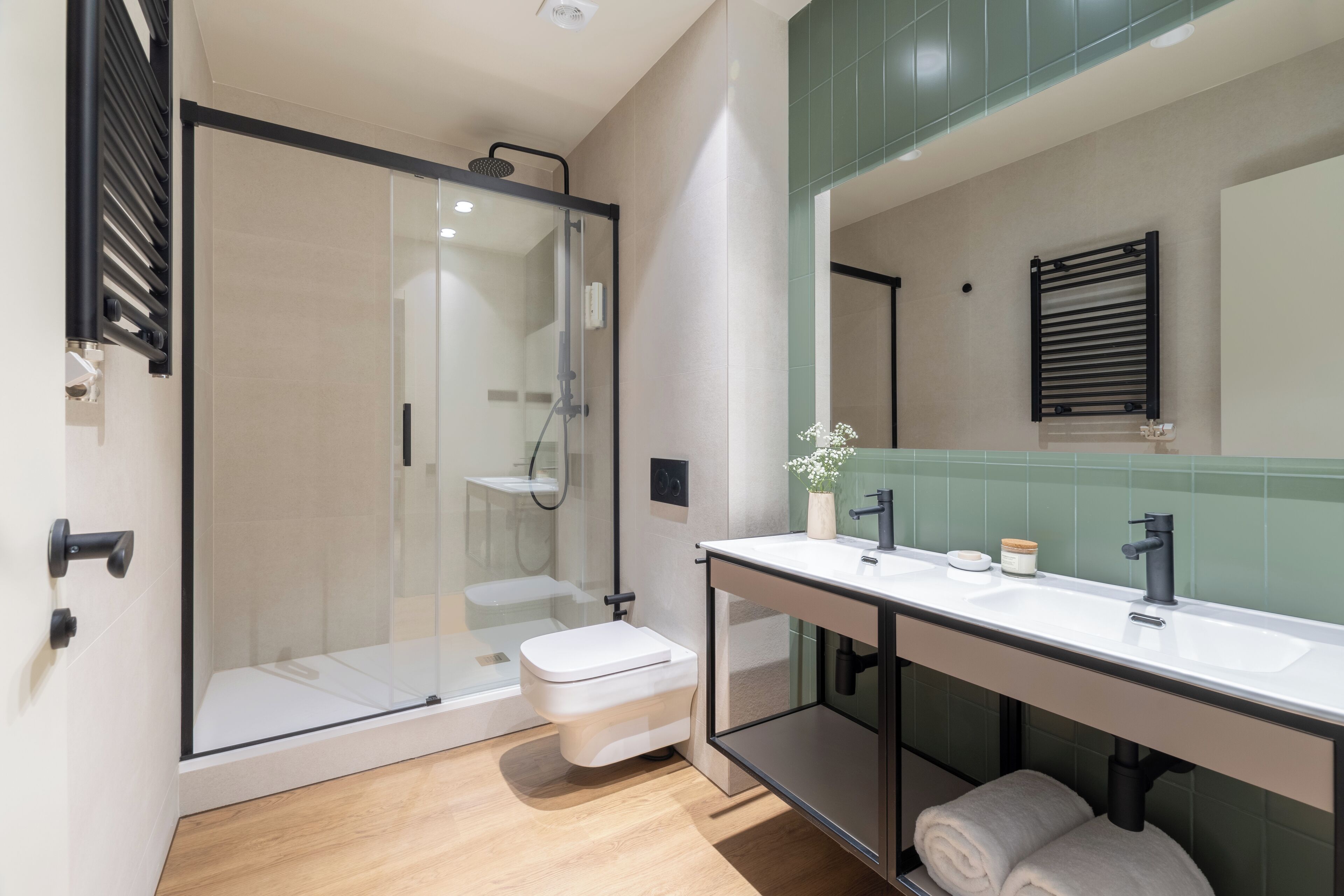 A modern bathroom with a glass shower enclosure, a white toilet, a vanity with a sink, and a mirror.