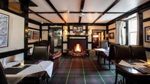 A cozy room with a fireplace, wooden beams, and plaid carpeting. - Cairndow Stagecoach Inn (Cairndow)