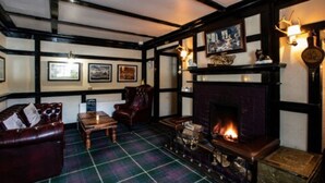 A traditional room with a fireplace, a plaid carpet, and wooden furniture. - Cairndow Stagecoach Inn (Cairndow)