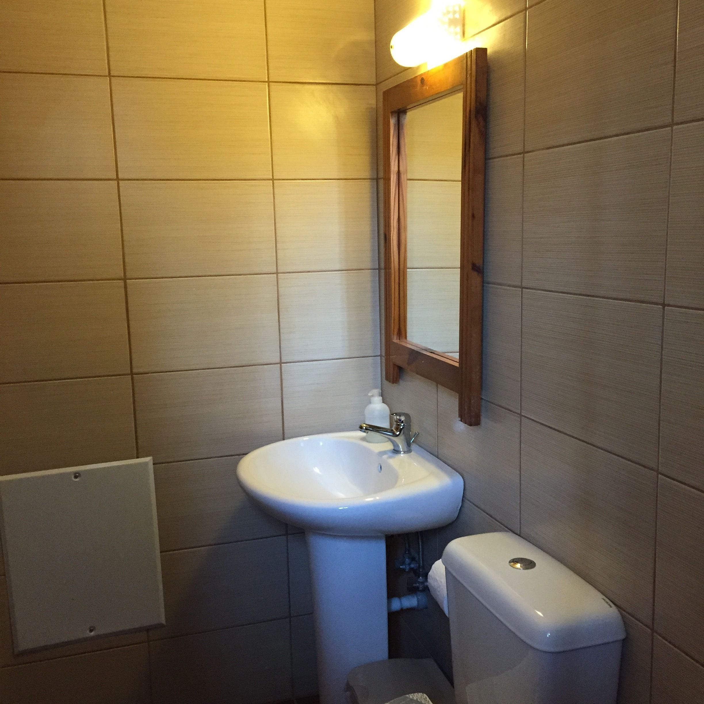 A bathroom with a white sink, a mirror, and a toilet.